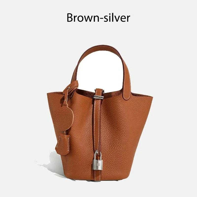 Sac à main seau Mendy en cuir véritable, marron, avec poignée courte et cadenas argenté.